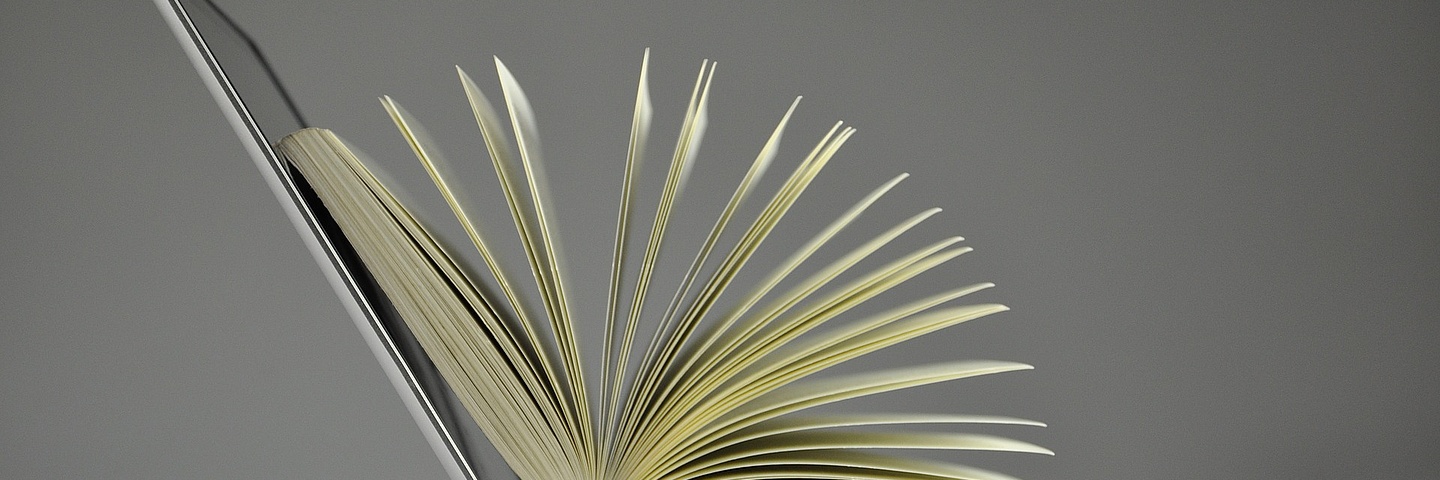 Laptop mit aufgeschlagenem Buch