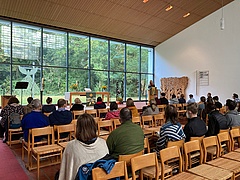 Teilenhemende am Gottesdiesnt im Kirchenraum "Zur Heimat" mit Blick zur Glasfront und dem Altar
