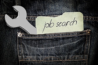 Hosentasche mit Schraubenschlüssel und Zettel: job search