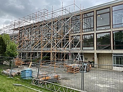 Ein Gerüst steht vor einem großen Backsteingebäude