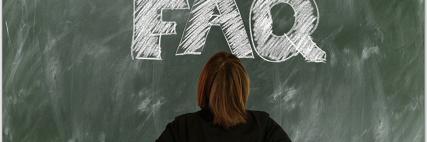 FAQ (Häufig gestellte Fragen) auf Tafel mit Person davor