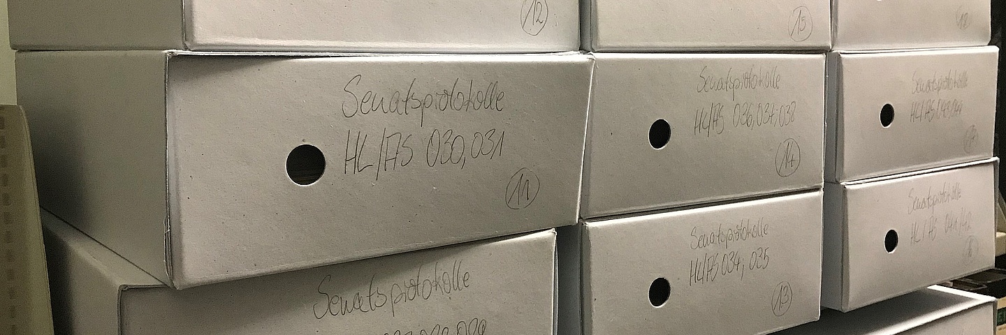 mehrere Archivkartons im Regal gestapelt