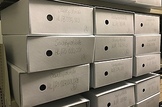 mehrere Archivkartons im Regal gestapelt