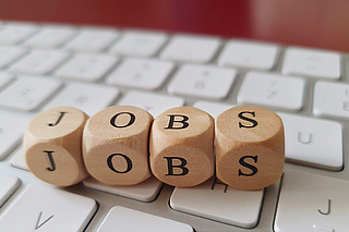 Vier Würfel mit Buchstaben, die den Schriftzug JOBS bilden