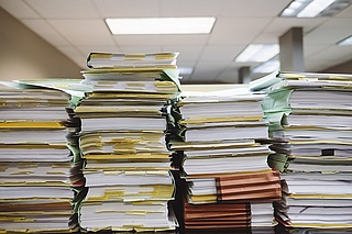 vier Stabel an Büchern mit vielen Zetteln zwischendrin, die auf einem Tisch liegen