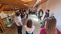 Studierende stehen in einem Raum im Kreis