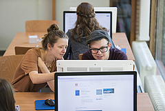 Zwei Studierende recherchieren in der Bibliothek