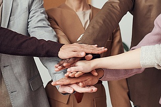 Ausschnitt: Gruppe bildet mit ihren Händen einen Turm